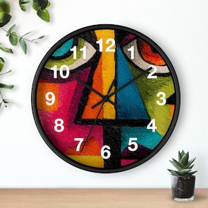 May include: A round wall clock with a black frame. The clock face features an abstract design with vibrant colors including pink, yellow, blue, and green. White numerals mark the hours.