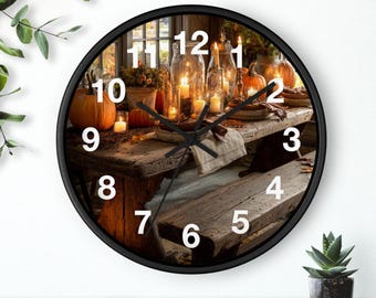 May include: A round wall clock with a black frame. The clock face features a rustic wooden table set for a fall feast, with pumpkins, candles, and plates. The clock hands are black, and the numbers are white.