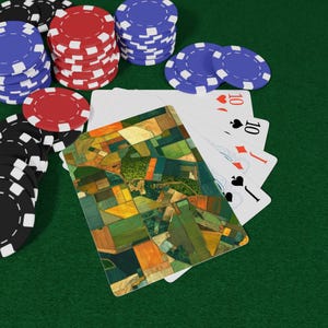 May include: A deck of playing cards with a custom back design featuring an aerial view of colourful agricultural fields, fanned out to reveal a ten of hearts, ten of spades, jack of diamonds, and jack of spades, surrounded by stacks of red, blue, and black poker chips.