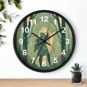 Könnte beinhalten: Eine runde Wanduhr mit schwarzem Rahmen und weißen Ziffern. Das Zifferblatt zeigt eine grün gehaltene Illustration einer Person mit langem Haar, die eine Krone und einen Umhang trägt und in einem Wald mit einem Hirsch einen Bogen hält.