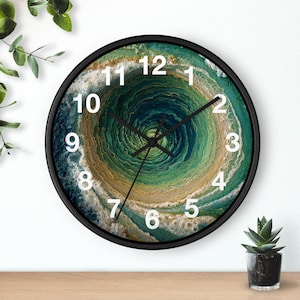 Peut inclure: Une horloge murale ronde avec un cadre noir et des aiguilles noires. Le cadran présente un motif abstrait tourbillonnant dans des tons de bleu sarcelle profond, de vert forêt et de beige sable, rappelant un tourbillon ou des vagues.