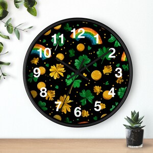 May include: A round black wall clock with a St. Patrick's Day theme. The clock face features a black background with gold coins, green shamrocks, yellow flowers, and rainbows. White numbers mark the hours.