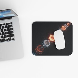 Könnte beinhalten: Schwarzes rechteckiges Mauspad mit einer weißen Computermaus. Das Mauspad zeigt eine Reihe von farbenfrohen, abstrakten, kreisförmigen Designs in Rot-, Orange- und Blautönen. Ein Laptop ist in der oberen linken Ecke sichtbar.