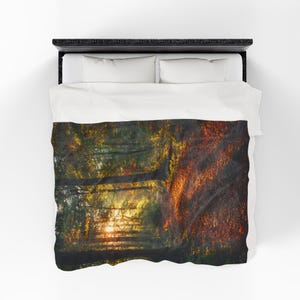 May include: A duvet cover depicting a landscape with a pathway leading to a sunset. The design uses green, yellow, and orange hues, creating a warm atmosphere. The bedding set includes a black bed frame and white pillows. The duvet cover is designed for a double bed.