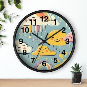 May include: A round wall clock with a black frame. The clock face features a light blue background with smiling yellow clouds, rainbows, and raindrops. The clock hands are black, and the numbers are in a black, stylized font.