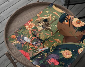Peut inclure: Un cadeau emballé avec un nœud marron et du papier d'emballage floral représentant un visage de femme et des fleurs colorées. Le cadeau est posé sur une table ronde en bois avec des ciseaux et une bobine de ruban.