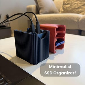 以下が含まれることがあります： 2つのミニマリストSSDオーガナイザー。1つは濃い青色でリブ加工、黒いコードが接続されています。もう1つは赤色でスロットがあります。「Minimalist SSD Organizer!」というテキストが灰色のボックスに表示されています。