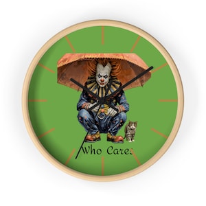 Può includere: Un orologio da parete rotondo con cornice in legno chiaro e quadrante verde. L'orologio presenta un clown sotto un ombrello, un gatto e il testo "Who Cares". Le lancette dell'orologio sono nere.