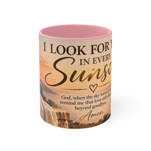 May include: A ceramic mug with a soft pink interior and rim. The exterior features a sunset landscape graphic with the text: I LOOK FOR YOU IN EVERY SUNSET. God, when the sky turns gold, remind me that love still shines beyond goodbye. Amen.