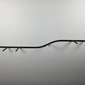 K&ouml;nnte beinhalten: Eine schwarze Klimmzugstange zur Wandmontage mit mehreren abgewinkelten Griffen. Die Stange hat ein gebogenes Design und ist an einer wei&szlig;en Wand befestigt. F&uuml;r das Oberk&ouml;rpertraining.