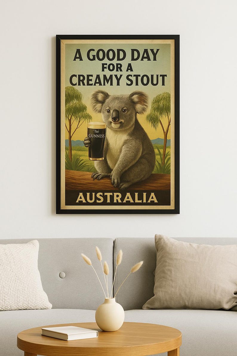 May include: Poster featuring a koala holding a pint of Guinness stout. The poster has the text "A Good Day for a Creamy Stout" and "Australia". The koala is sitting on a log with trees in the background. The poster is framed in black.