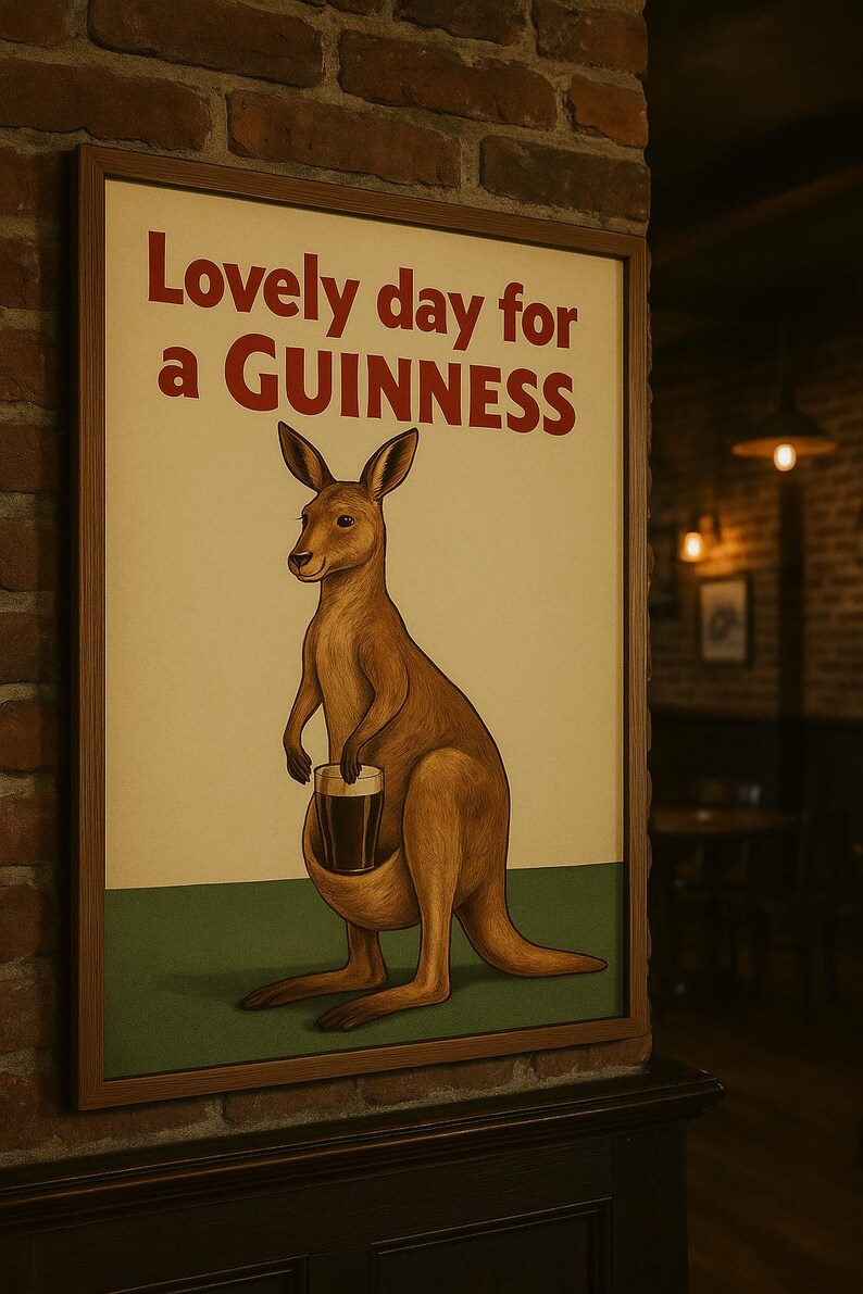 Puede incluir: P&oacute;ster enmarcado de estilo vintage con un canguro marr&oacute;n sosteniendo una pinta de Guinness. El texto "Lovely day for a GUINNESS" es rojo. El fondo es crema con una base verde. Marco de madera.