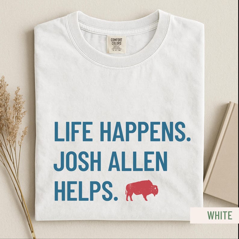 May include: White t-shirt with the text "LIFE HAPPENS. JOSH ALLEN HELPS." in blue, and a red buffalo graphic. The shirt is made of a soft material and has a crew neck.