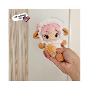 Könnte beinhalten: Eine handgefertigte Schafpuppe mit weißem Körper, rosa Haaren und braunen Akzenten. Die Puppe hat große, schwarze Augen und wird in einer Hand gehalten. Das Bild enthält den Text "PDF PATTERN ONLY".