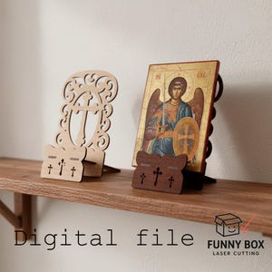 Puede incluir: Dos portadores de iconos de madera, uno de color claro con un diseño de cruz decorativo y otro de color oscuro que sostiene un icono de un ángel. La imagen está en un estante de madera. El texto "Digital file" es visible.