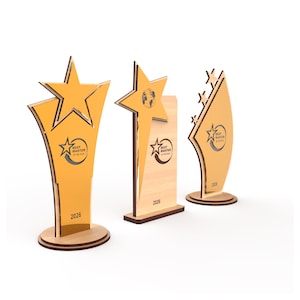 K&ouml;nnte beinhalten: Drei Holztroph&auml;en mit Stern-Design. Die Troph&auml;en sind gold- und braunfarben und tragen den Text "Best Master of the Year" und das Jahr "2026". Die Troph&auml;en stehen vor einem wei&szlig;en Hintergrund.