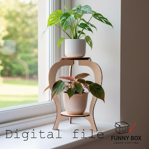 May include: A two-tiered wooden plant stand with two potted plants. The top plant has large green leaves, and the bottom plant has green and red leaves. The stand is made of light-colored wood and has a decorative design. Text on the image reads "Digital file".