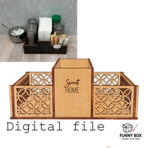 Może przedstawiać: Drewniany organizer z geometrycznymi wzorami wyciętymi laserowo i napisem "Sweet Home". Organizer posiada przegródki na różne przedmioty, w tym serwetki, saszetki z cukrem i przyprawy. Projekt obejmuje część centralną i dwie boczne.