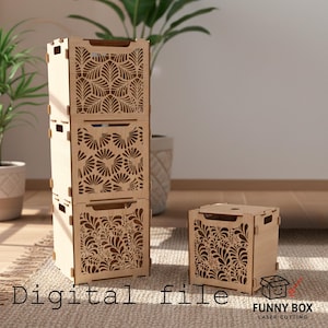 May include: Three stacked, light-coloured wooden storage boxes with intricate floral cutouts, alongside a single box. The boxes are on a neutral-toned rug. The text "Digital file" and "FUNNY BOX LASER CUTTING" are visible.