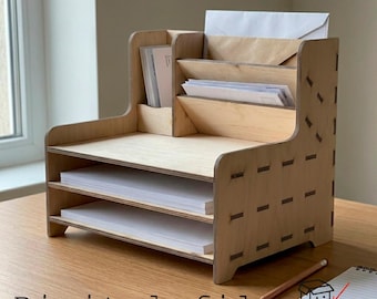 May include: A light-colored wooden desk organizer featuring two horizontal paper trays and a vertical tiered mail sorter. The structure is assembled with visible interlocking joints. The text "Digital file" and "FUNNY BOX LASER CUTTING" appear at the bottom.