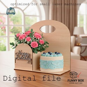 Może przedstawiać: Drewniany wyświetlacz wycinany laserowo z różowymi różami i małym ciastem z niebieskim lukrem. Wyświetlacz zawiera tekst "Happy Birthday" i "Digital file". Projekt jest zoptymalizowany pod kątem małych maszyn laserowych. Wymiary: 30,5 cm x 30,5 cm.