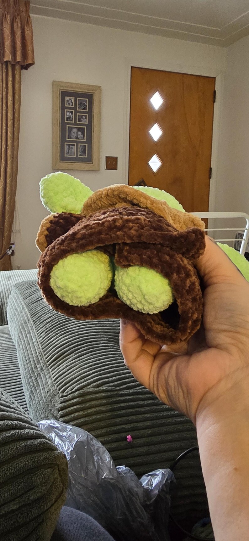 Puede incluir: Un juguete de taco de ganchillo hecho a mano con dos mitades de aguacate verdes. La concha del taco es marr&oacute;n y el aguacate es verde brillante. El juguete es suave y afelpado, para ni&ntilde;os.