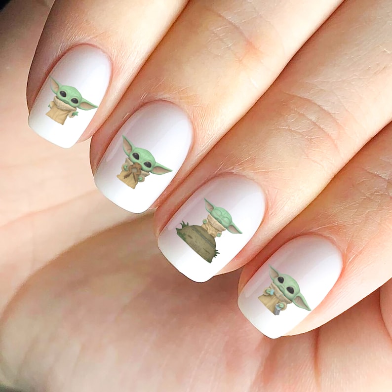 May include: Set of five white nail decals featuring a cartoon image of a green alien character from the Star Wars franchise.