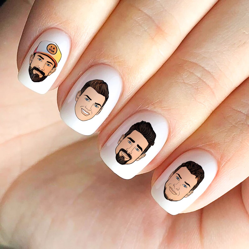 May include: Four fingernails with cartoon faces of men on them. The faces are drawn in a simple style with black outlines and brown hair. The nails are painted white.