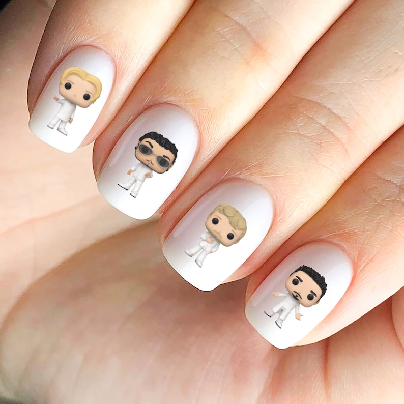 May include: Four white nail decals featuring cartoon figures wearing white clothing. The figures have different hairstyles and facial features.