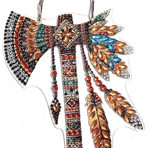May include: A decorative pendant necklace featuring a Native American-inspired design. The pendant is shaped like an axe with colorful beadwork, rhinestones, and feather accents. The necklace has a silver chain.