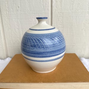 May include: A handmade wooden sign with the text "Welcome" in a whimsical font. The sign is painted white with a distressed finish and features a decorative floral design in shades of pink and green. It measures approximately 12 inches wide.