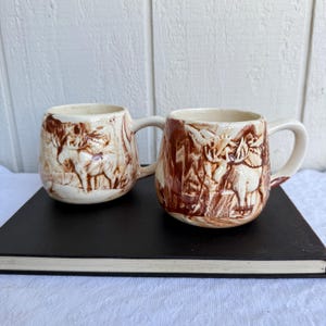 May include: A set of three ceramic mugs with a speckled, matte finish. The mugs are in shades of cream, light gray, and dark gray. Each mug has a simple, minimalist design, perfect for coffee or tea.