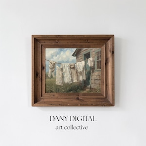 May include: A framed vintage art print showing white laundry hanging on a washing line in front of a weathered building. The artwork is set against a backdrop of a blue sky with clouds and green grass. The frame is made of dark brown wood. The text "DANY DIGITAL art collective" is at the bottom.