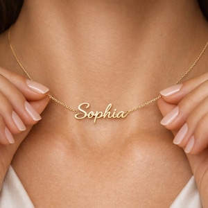 May include: A delicate gold necklace featuring the name "Sophia" in elegant cursive script. The pendant hangs from a fine chain, creating a personalized and stylish accessory. The necklace is a beautiful piece of jewelry.