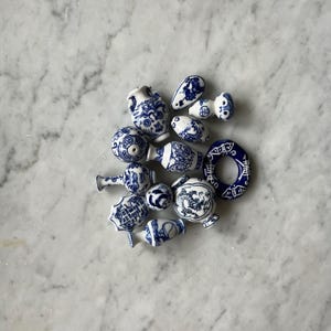 May include: A collection of small, blue and white porcelain vases and ornaments with intricate designs. The ornaments are in various shapes, including round, oval, and vase-like.