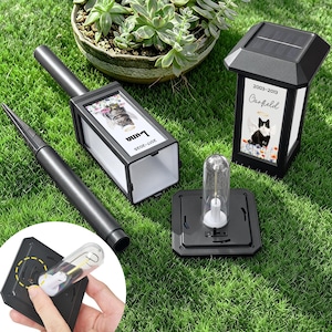 May include: Black solar-powered memorial lanterns with personalized pet photos. One lantern has a photo of a cat named Luna, the other a cat named Garfield. Includes a stake for ground placement and a replacement bulb.