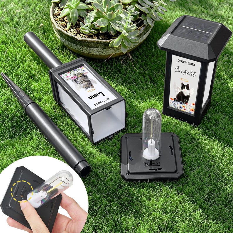 May include: Black solar-powered memorial lanterns with personalized pet photos. One lantern has a photo of a cat named Luna, the other a cat named Garfield. Includes a stake for ground placement and a replacement bulb.