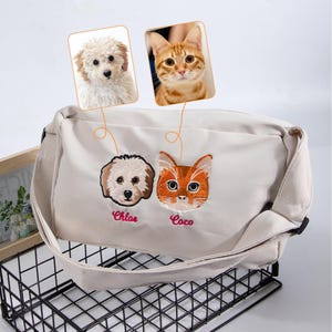 May include: Beige crossbody bag featuring embroidered dog and cat faces with the names "Chloe" and "Coco" below. The bag has a long strap and includes images of a dog and cat above the embroidered faces.