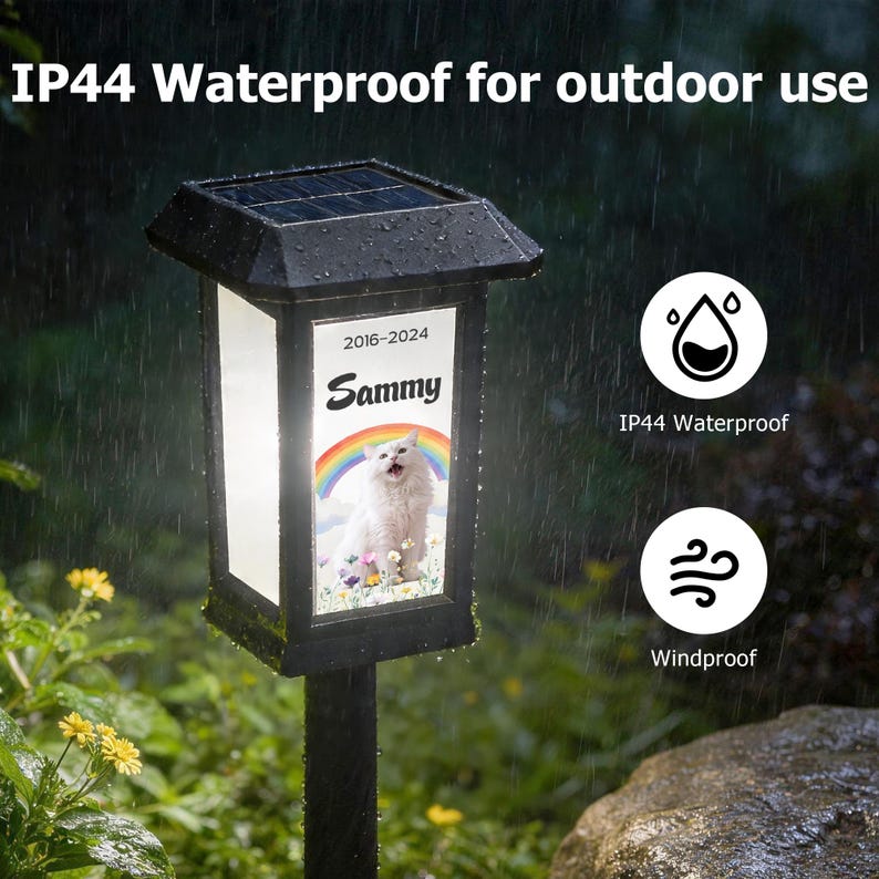 May include: Black solar-powered outdoor light with a rectangular frame. The light features a picture of a cat with the name "Sammy" and the years "2016-2024". The text "IP44 Waterproof for outdoor use" is at the top.