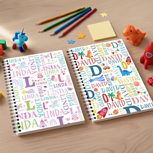 Puede incluir: Dos cuadernos con espiral con diseños personalizados. Uno presenta el nombre "LINDA" en varios colores con ilustraciones de unicornios y castillos. El otro cuaderno muestra "DAVID" con gráficos de dinosaurios y cohetes. Lápices y juguetes están dispersos.