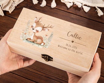 May include: A light wooden box with a deer illustration and the name "Callie" engraved on the lid. The box also includes the date "18.04.2024" and the phrase "Welcome to the world."