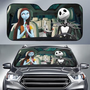 May include: Black car sunshade featuring characters from The Nightmare Before Christmas. Sally is holding a rose, Jack Skellington is driving, and Zero is in the back seat. The sunshade is black with a mesh design.