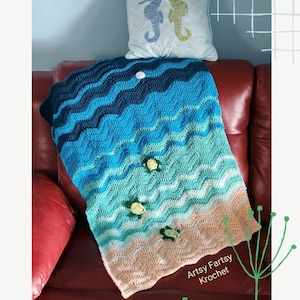 May include: A handmade crochet blanket with a beach theme. The blanket features wavy patterns in shades of blue, representing the ocean, and beige for the sand. Adorned with small turtle appliqués, it's placed on a red sofa with a seahorse pillow.