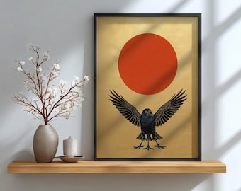 May include: Framed art print featuring a black crow with outstretched wings beneath a large red circle on a gold background. The artwork is in a black frame and is displayed on a wooden shelf with a vase and candle.