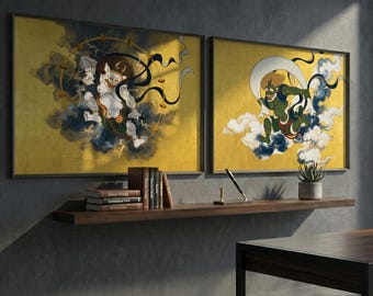 May include: Two framed wall art pieces with gold backgrounds and Japanese-inspired illustrations. One features a white and brown figure with black ribbons, the other a green figure with a crescent moon. Both are set against a backdrop of clouds and dark accents.