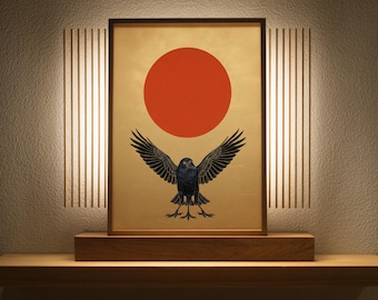 May include: A rectangular framed print featuring a black crow with wings spread wide, positioned below a large solid red circle on a gold background. The artwork is displayed on a wooden base, flanked by vertical light strips on the wall.