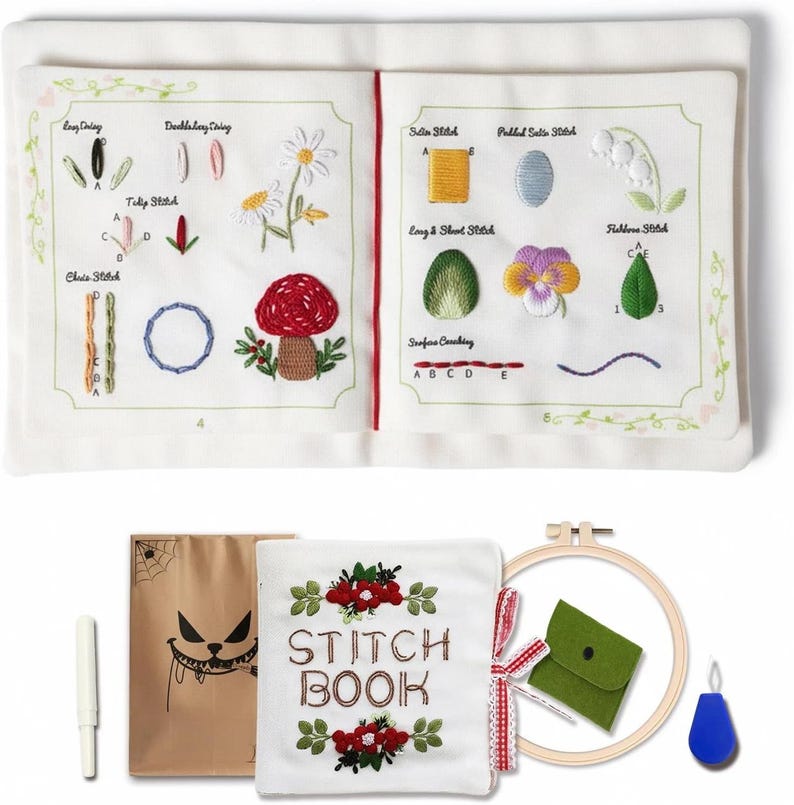 Puede incluir: Un libro de costura blanco abierto que muestra ejemplos de puntadas bordadas, incluyendo un hongo y flores. Incluye una aguja, una bolsa marr&oacute;n con una cara de monstruo, una bolsa verde y un bastidor de bordado de madera.