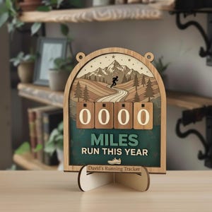 May include: Wooden running tracker with a mountain scene and the text "MILES RUN THIS YEAR." The tracker has a space to display the number of miles run. The base reads "David's Running Tracker."