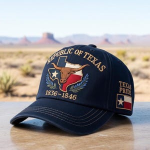 Op de afbeelding: Marineblauwe baseballcap met borduursel. Het toont de omtrek van de staat Texas, een longhorn en de tekst "REPUBLIC OF TEXAS 1836-1846". De cap toont ook "TEXAS PRIDE" en de vlag van Texas.
