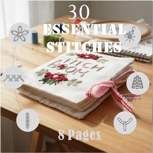 Puede incluir: Un "Stitch Book" de tela blanca con flores rojas y hojas verdes bordadas, atado con una cinta roja y blanca. El libro est&aacute; abierto, mostrando p&aacute;ginas. El texto dice "30 Essential Stitches" y "8 Pages".